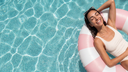 Woman lounging on a pink and white striped pool float in a pool.
